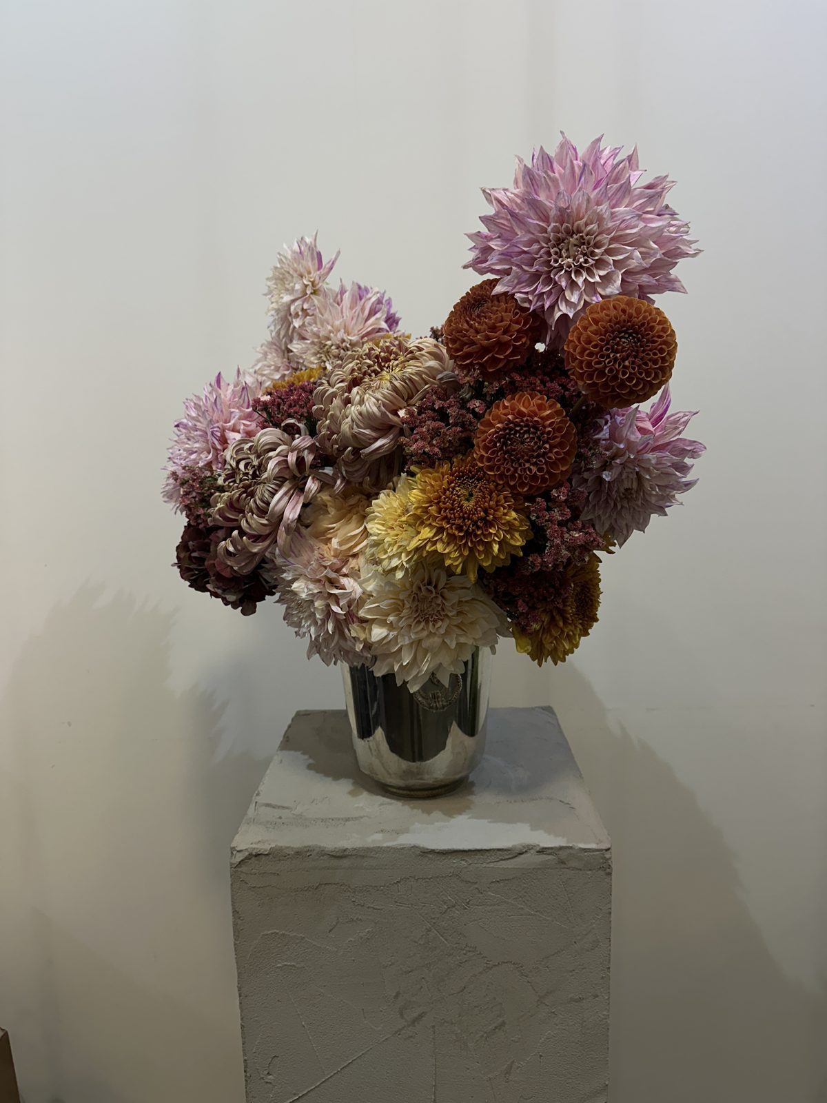 FLWR arrangement of pink and orange dahlias, spider chrysanthemums and statice in a silver vase