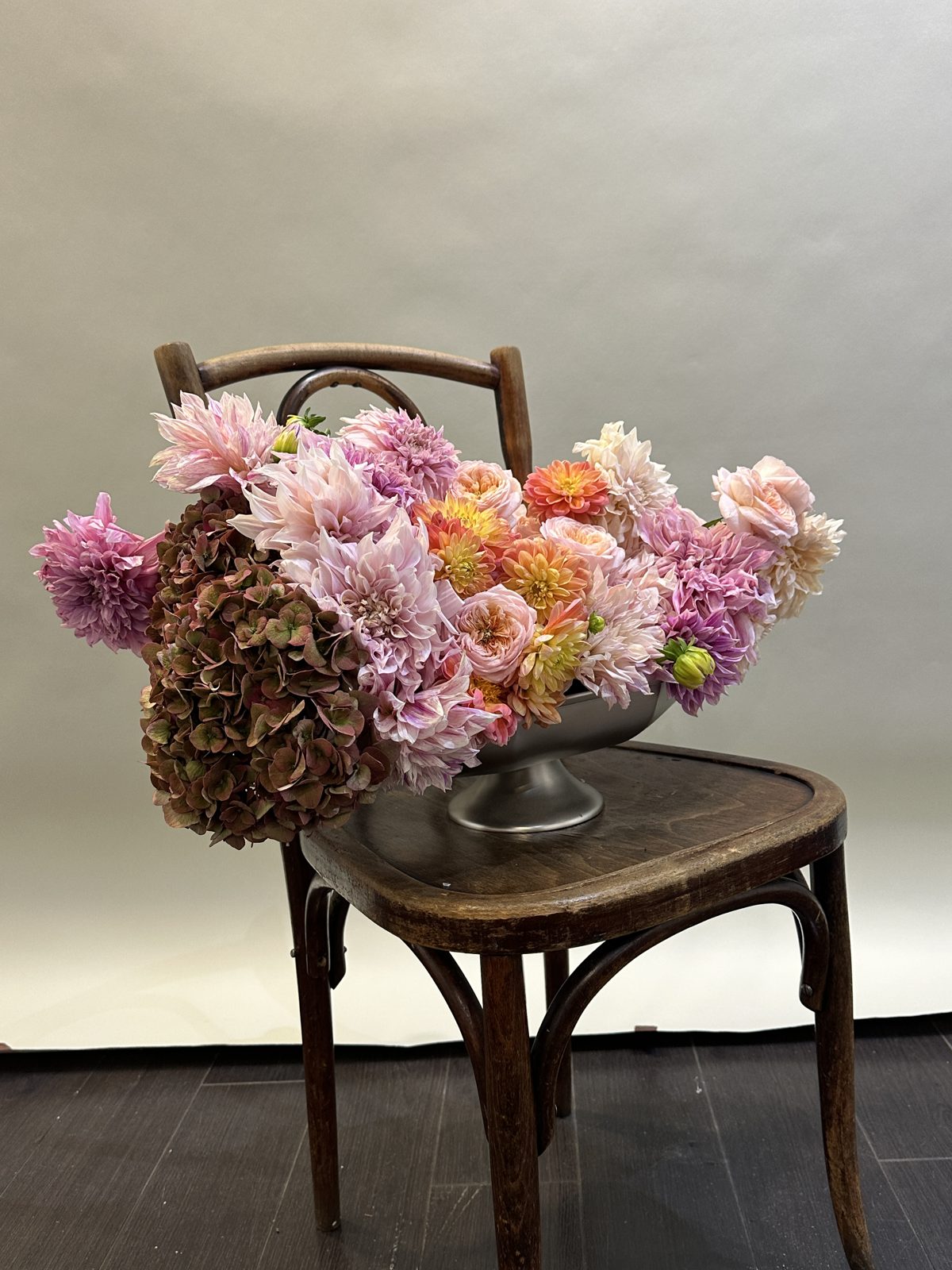 FLWR arrangement in a bowl: café au lait dahlias, peach garden roses and burgundy hydrangea